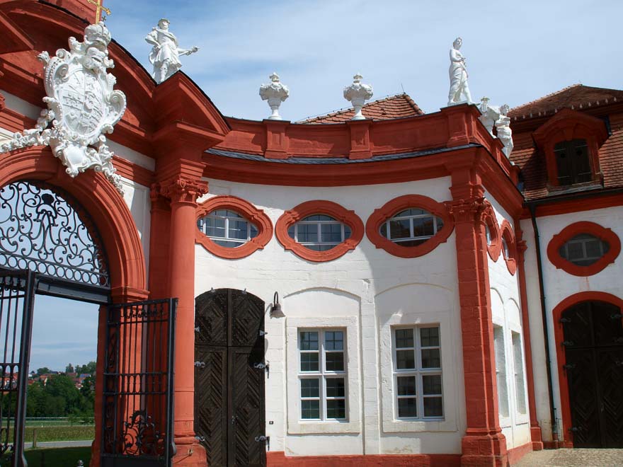 Das Fürstbischöfliche Wappen leuchtet weiß in der rot-weißen Eingangspforte über dem geöffneten Stahltor.