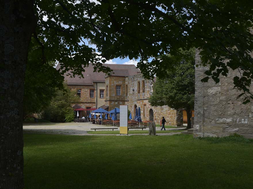 Die Giechburgmauern von innen, mit den blauen Sonnenschirmen und Bierbänken des Restaurants.